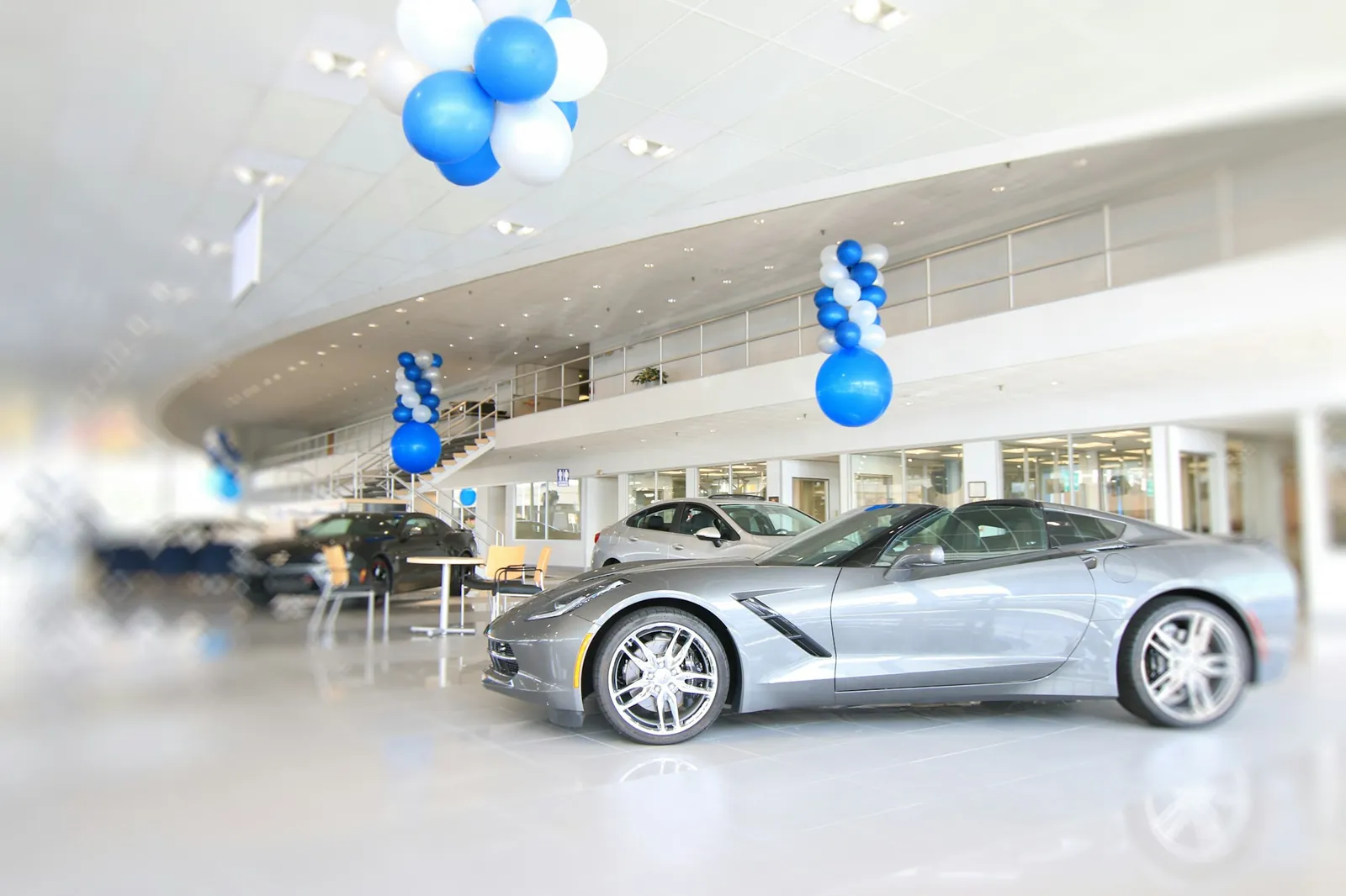 Sales consultant walking a customer through a dealership showroom towards a parked car