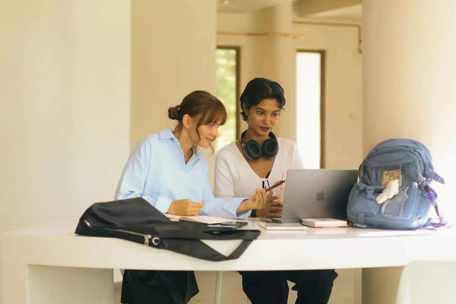 Admissions adviser talking with a prospective student at a small table in a bright campus atrium