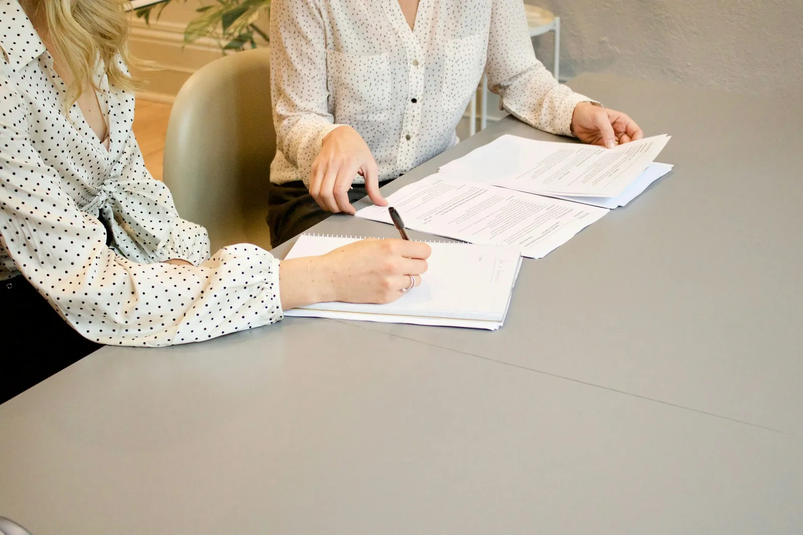 Financial adviser reviewing a printed document with a client at a bright office table