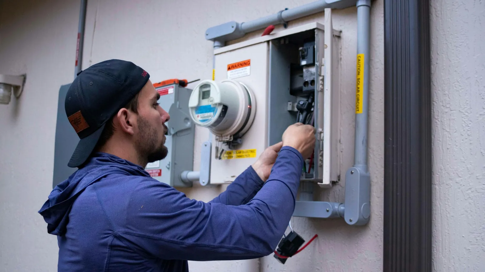 Technician sitting in the open door of a work van checking his phone between jobs on a residential street