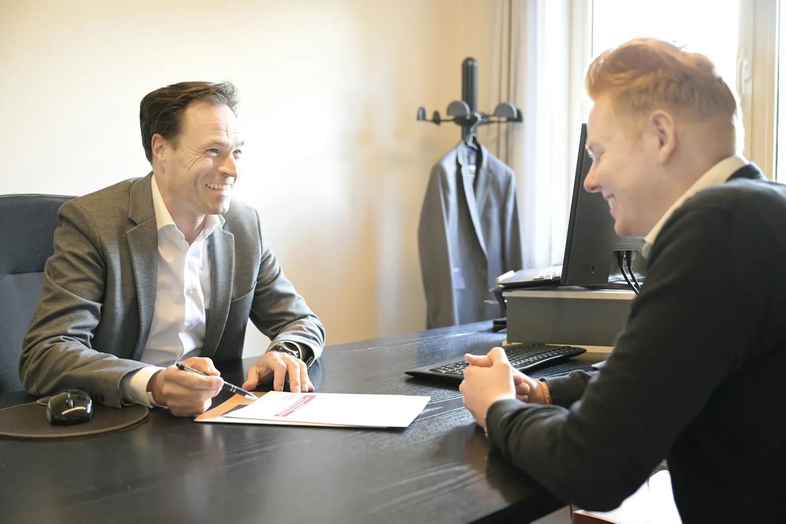 Senior professional reading a printed brief at a desk by the window of a small firm